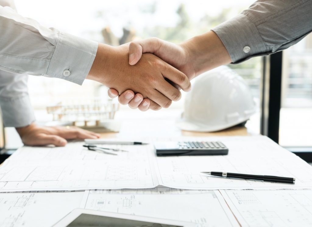 Two hands shaking in agreement on a home build strategy