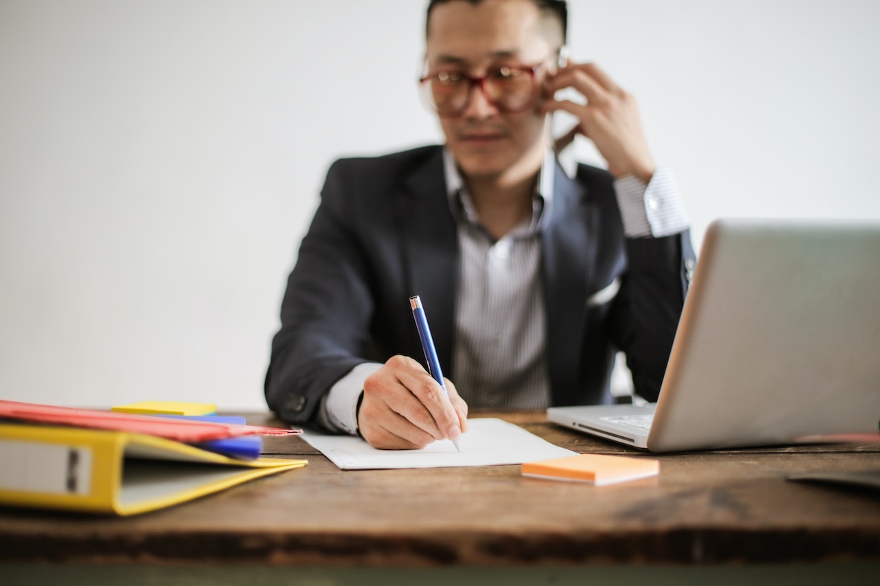 Man with glasses on phone taking notes